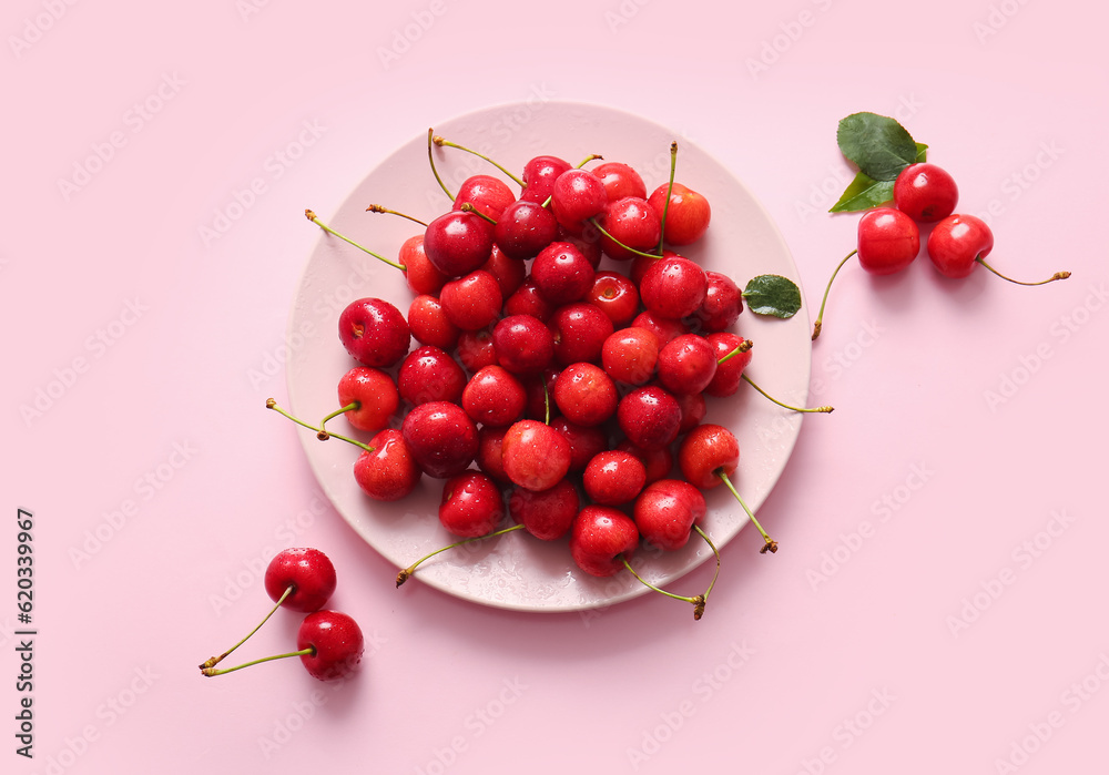 Plate of sweet cherries on pink background