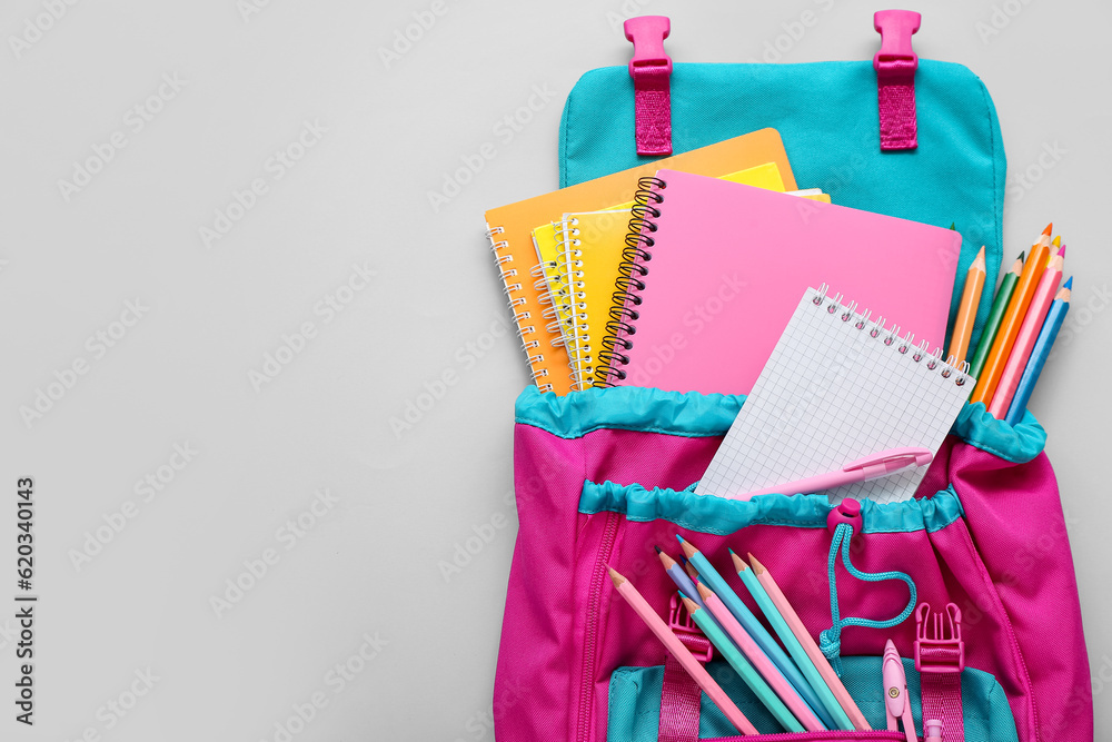 Backpack with blank notebook and stationery on grey background