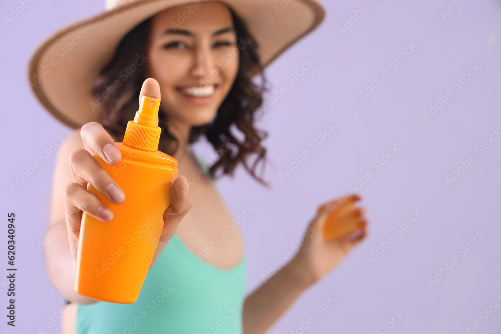 Young woman with sunscreen cream on lilac background, closeup