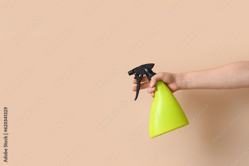 Gardener with spray bottle on beige background