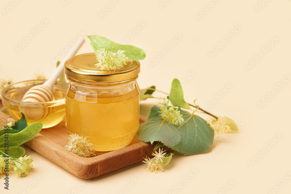 Wooden board with glass bowl and jar of linden honey on light background