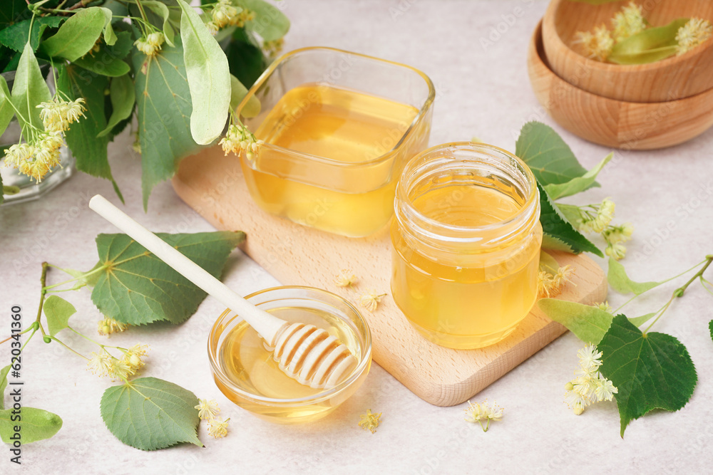 Glass bowls and jar with linden honey on white background