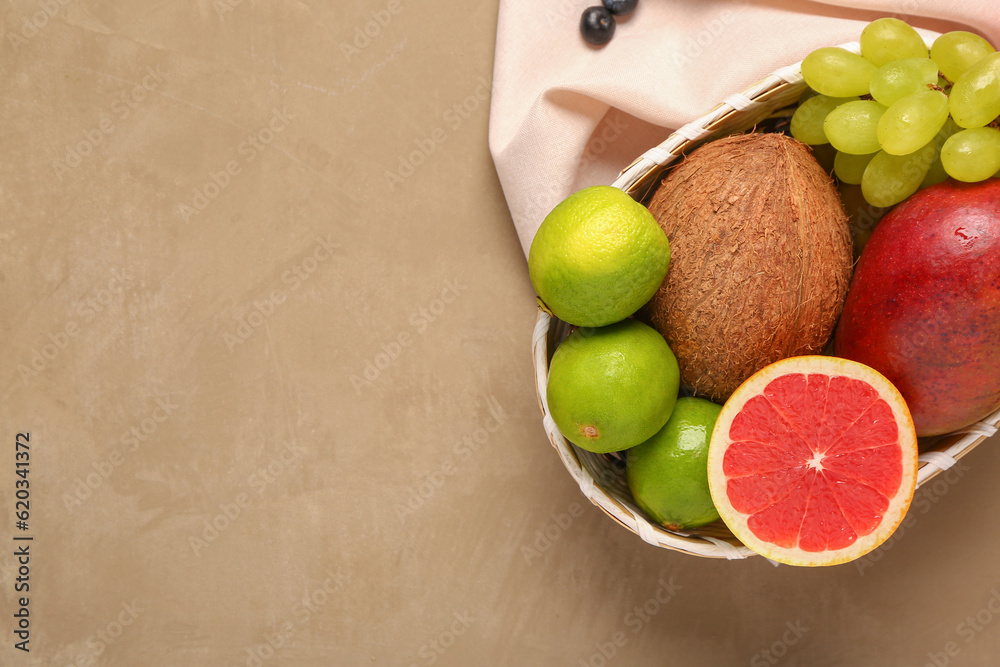 Wicker bowl with different fresh fruits and vegetables on brown background, closeup