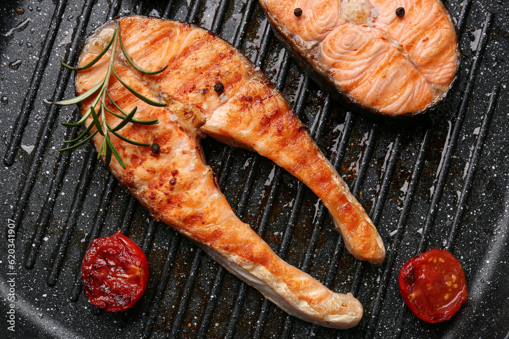 Tasty grilled salmon steaks in frying pan, closeup