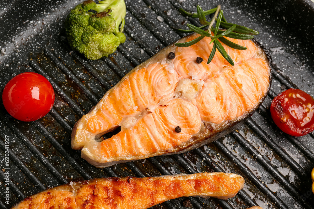 Tasty grilled salmon steaks in frying pan, closeup