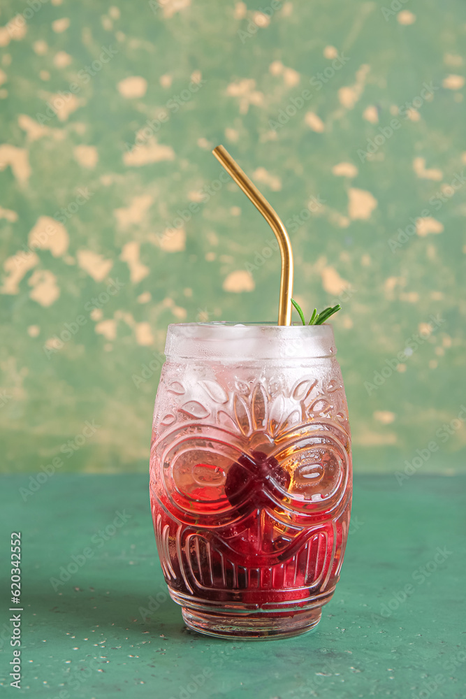 Glass of tasty cherry lemonade with rosemary on green table