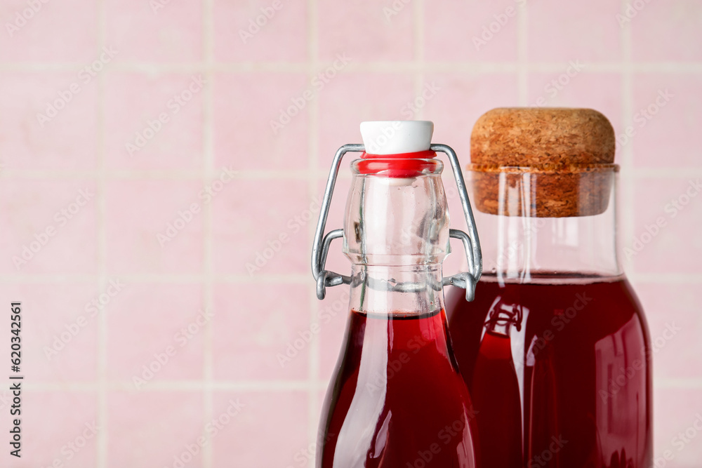 Bottles with sweet cherry liqueur on pink tile background