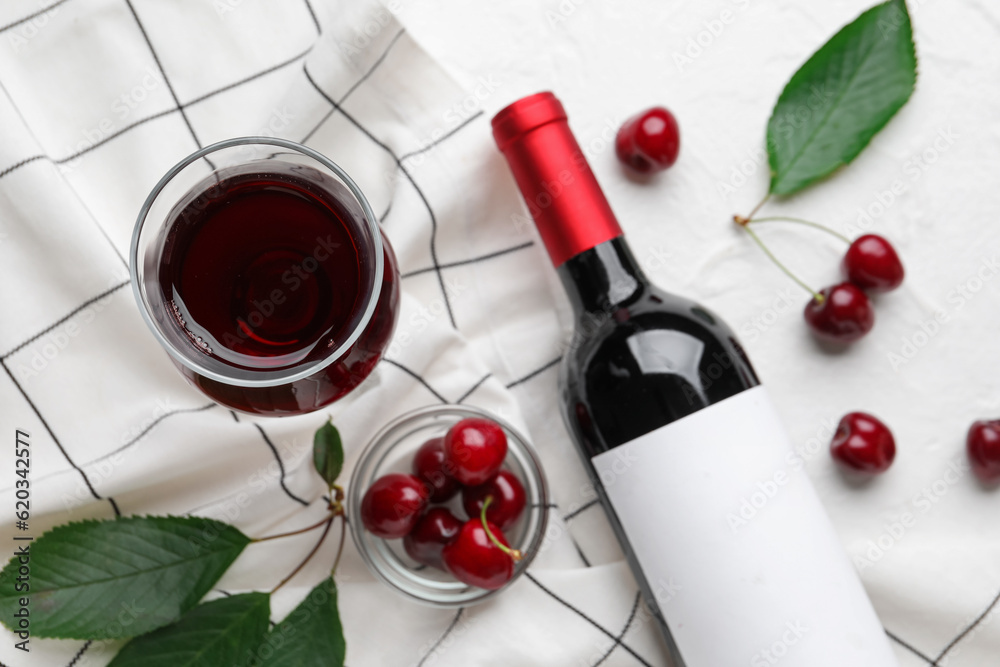 Glass and bottle with sweet cherry liqueur on white background