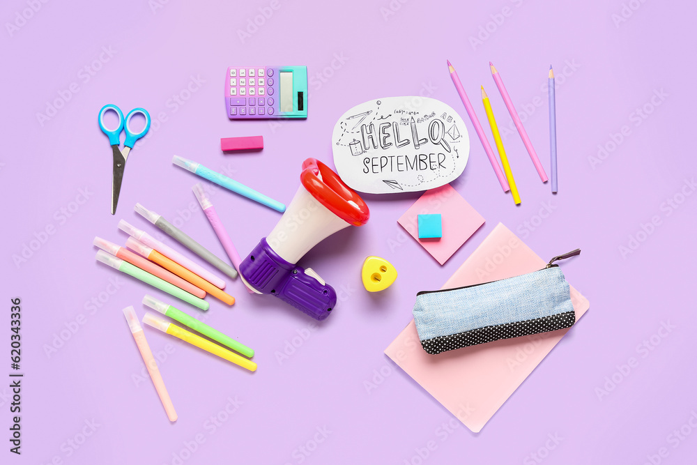 Stationery, megaphone and sheet with text HELLO SEPTEMBER on lilac background