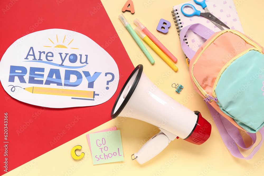 Backpack, stationery, megaphone and sheet with question ARE YOU READY? on color background