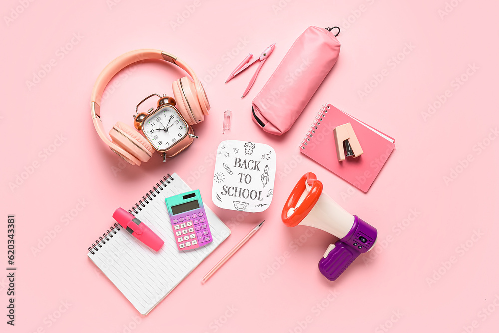 Headphones, alarm clock, megaphone and sheet with text BACK TO SCHOOL on pink background