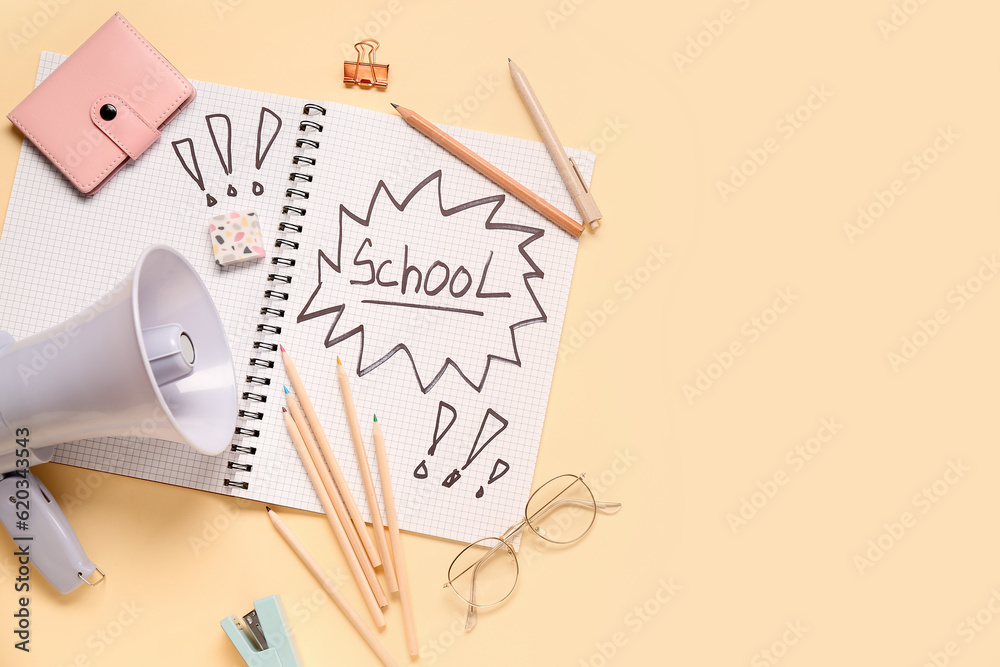 Stationery, megaphone and notebook with word SCHOOL on pale yellow background