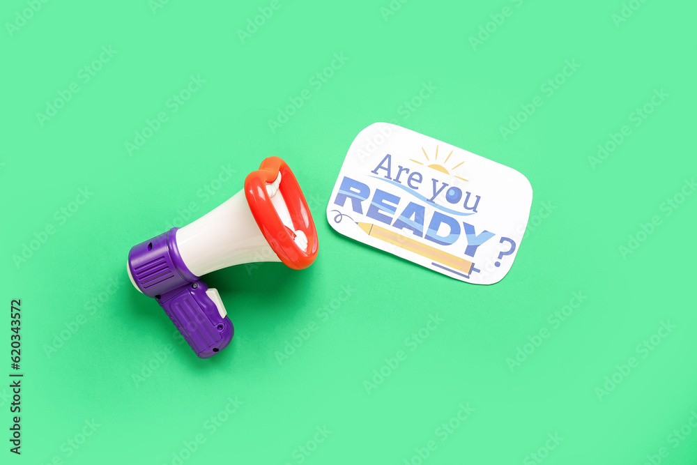 Megaphone and sheet with question ARE YOU READY? on green background