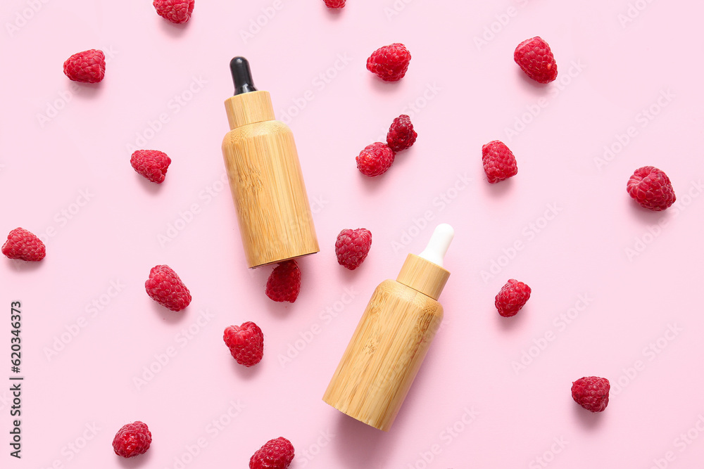 Bottles of cosmetic raspberry oil on pink background