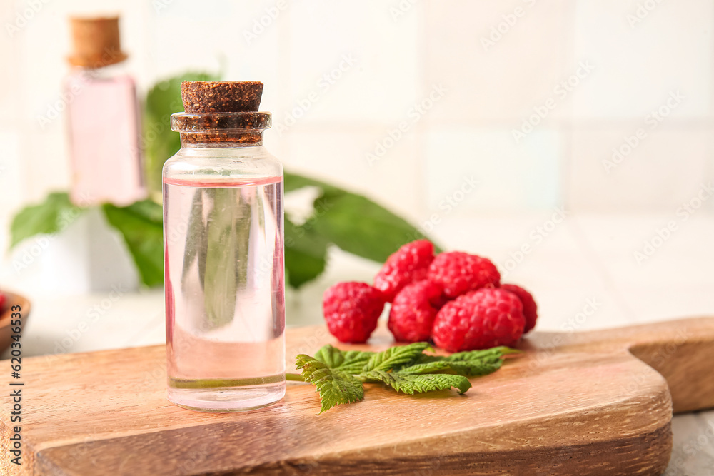 Bottle of cosmetic raspberry oil on white background, closeup