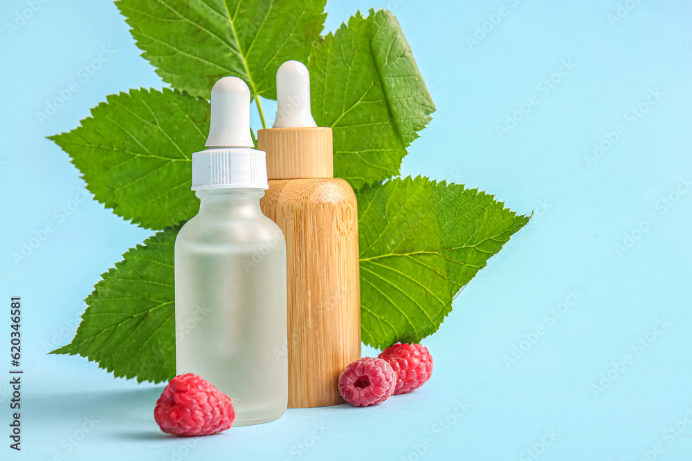 Bottles of cosmetic raspberry oil on blue background