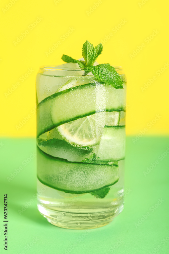 Glass of fresh cucumber mojito on color background