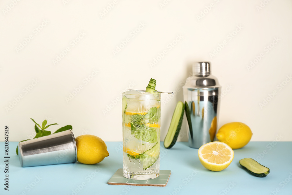 Glass of mojito with bartender tools on blue table near white wall