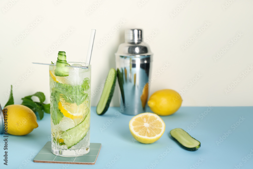 Glass of mojito with bartender tools on blue table near white wall