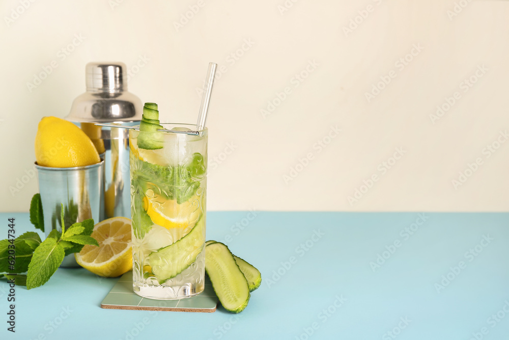 Glass of mojito with bartender tools on blue table near white wall