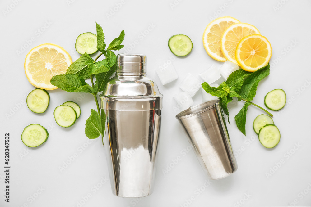 Cocktail shaker and jigger with mojito ingredients on light background