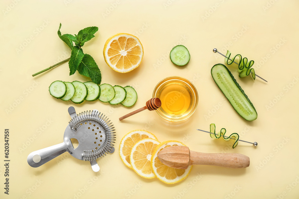 Fresh ingredients for cucumber mojito with strainer and juicer on yellow background