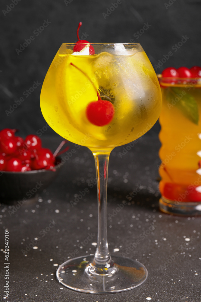 Glass of tasty cocktail with maraschino cherries on grey background