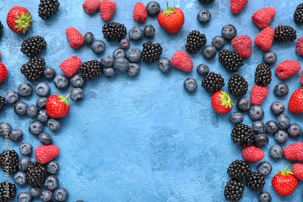 Frame made of different fresh berries on blue background