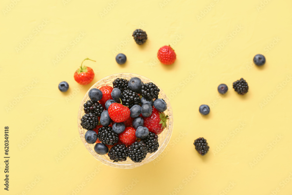 Bowl with fresh berries on yellow background