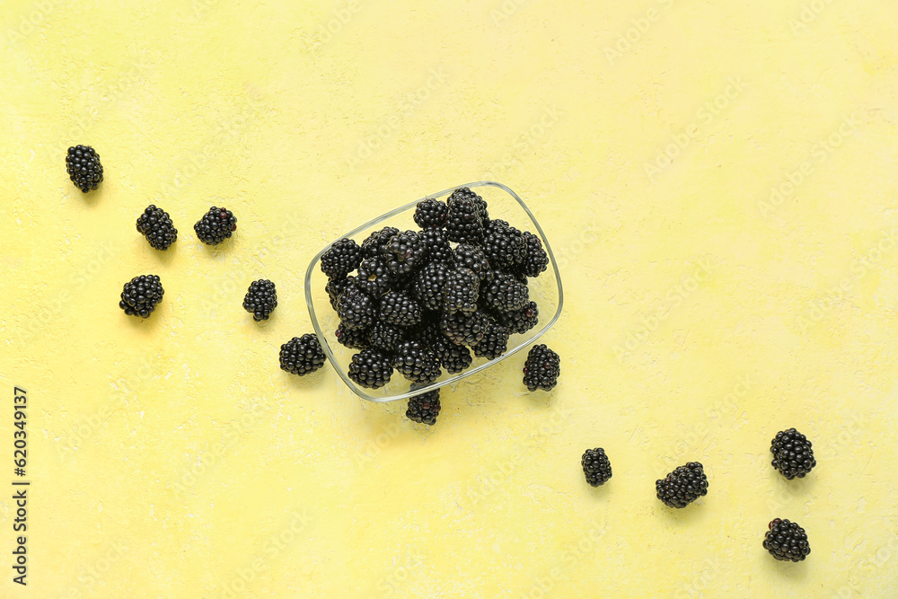 Bowl with fresh blackberry on yellow background