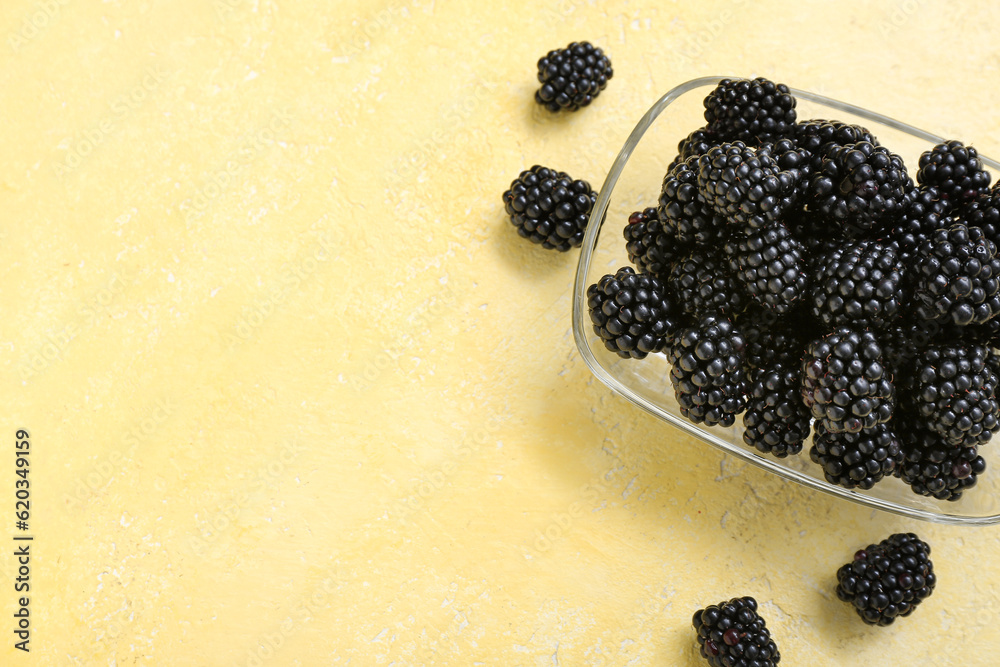 Bowl with fresh blackberry on yellow background, closeup