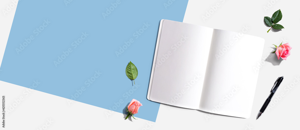 Open notebook or diary with a pen from above with rose buds- flat lay