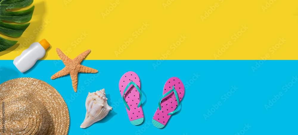 Summer concept with a straw hat, sunblock, starfish, beach sandals and shell overhead view