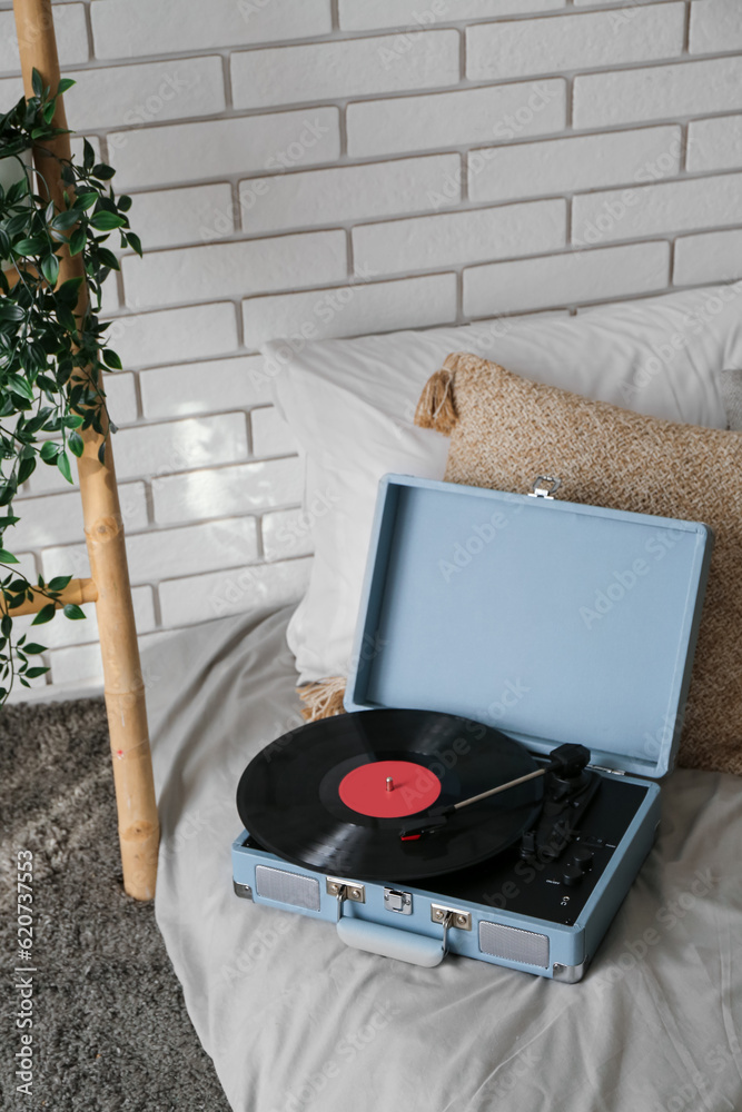 Record player with vinyl disk on bed in room