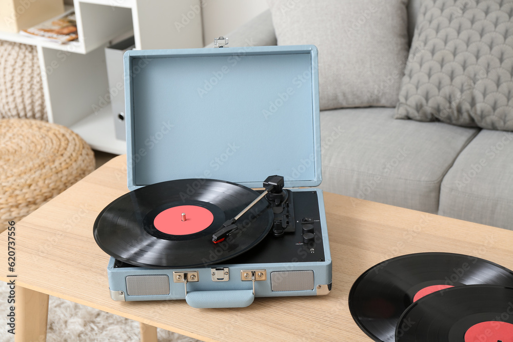 Record player with vinyl disks on table in living room