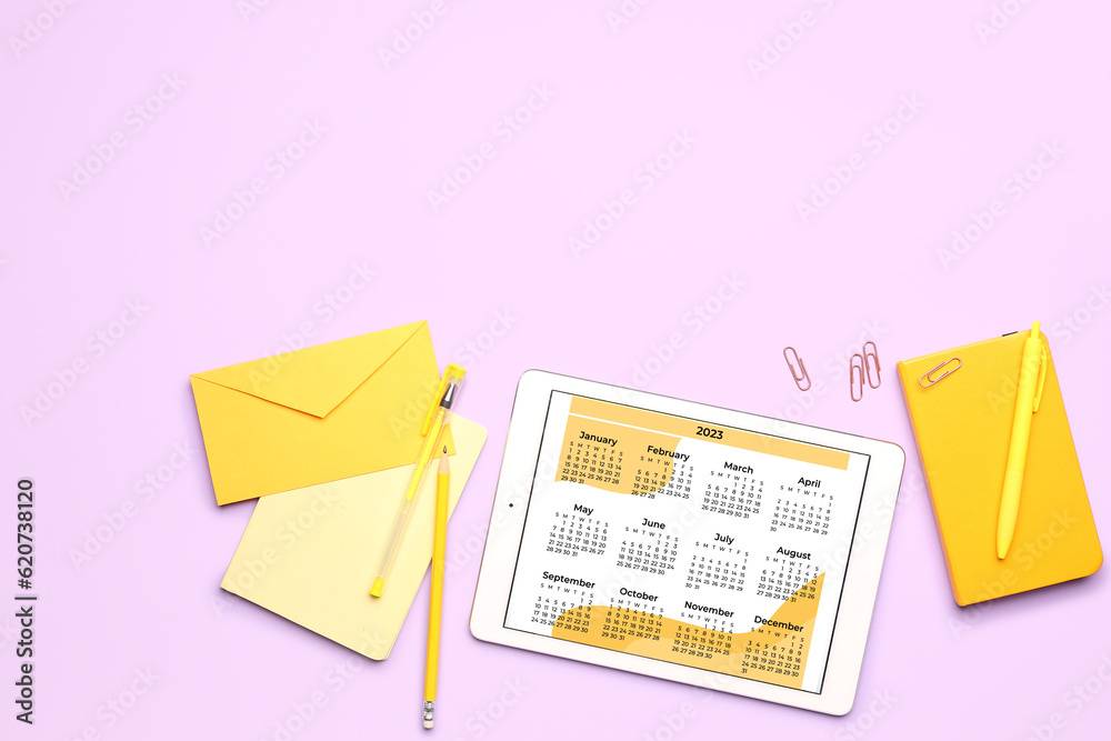 Modern tablet computer with calendar, notebook, envelope and stationary on lilac background