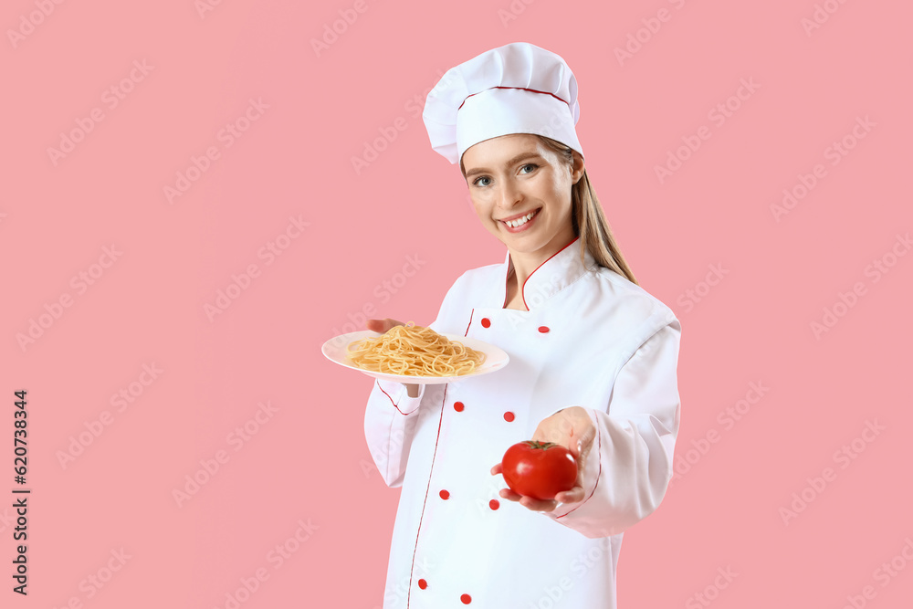 Female chef with tasty pasta and tomato on pink background