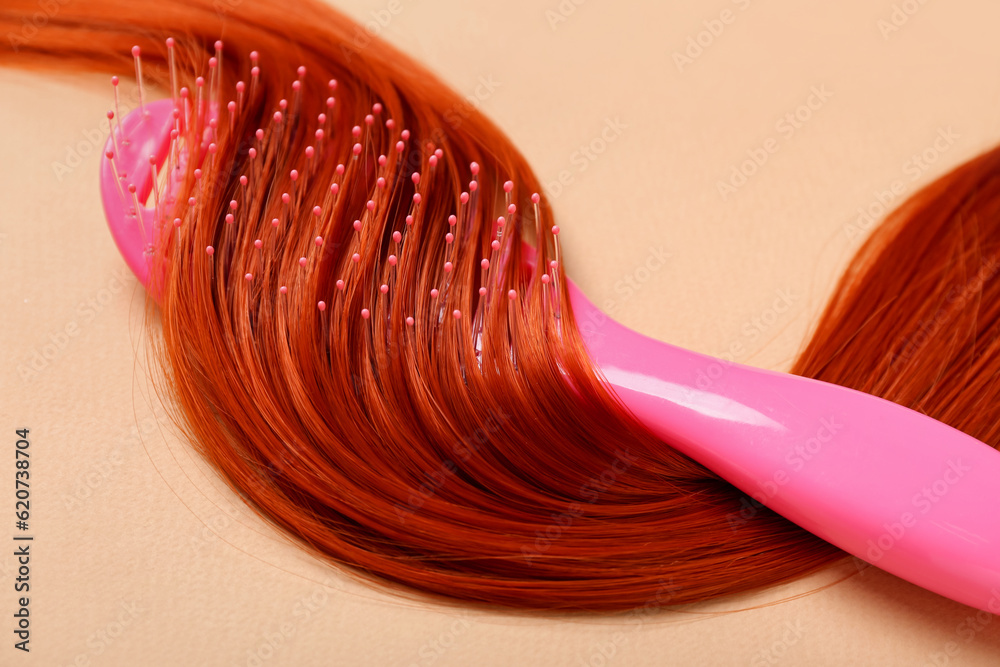 Ginger hair strand and brush on color background, closeup