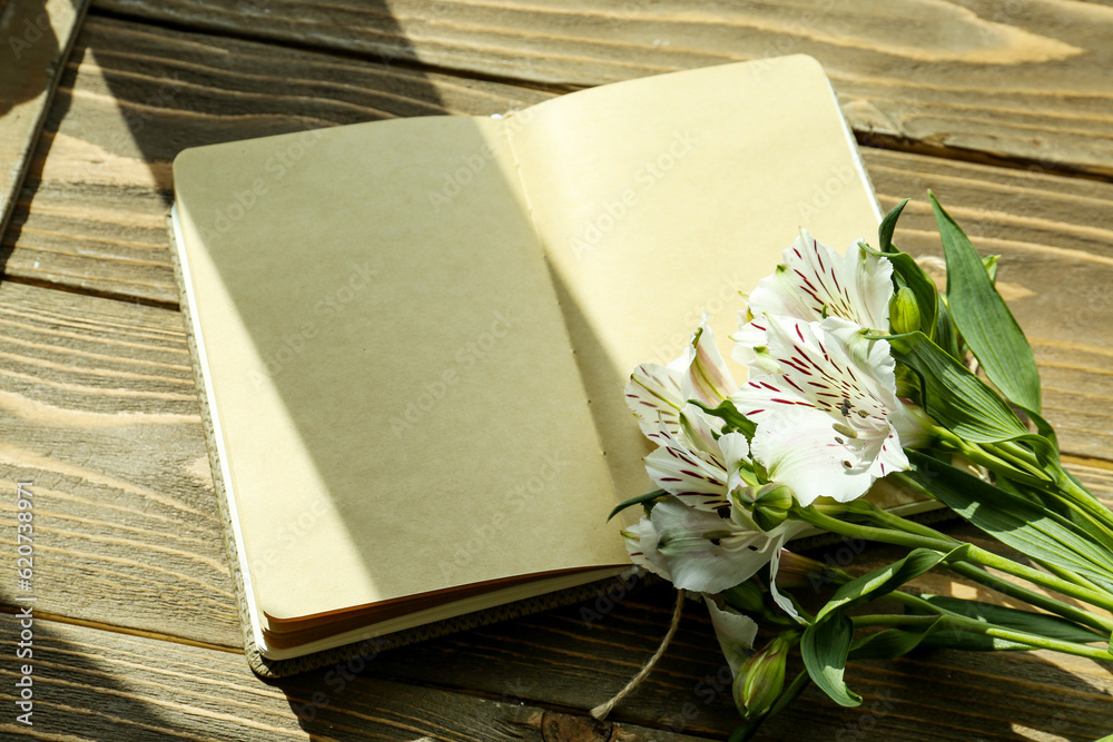 Blank open notebook and beautiful alstroemeria flowers on wooden background