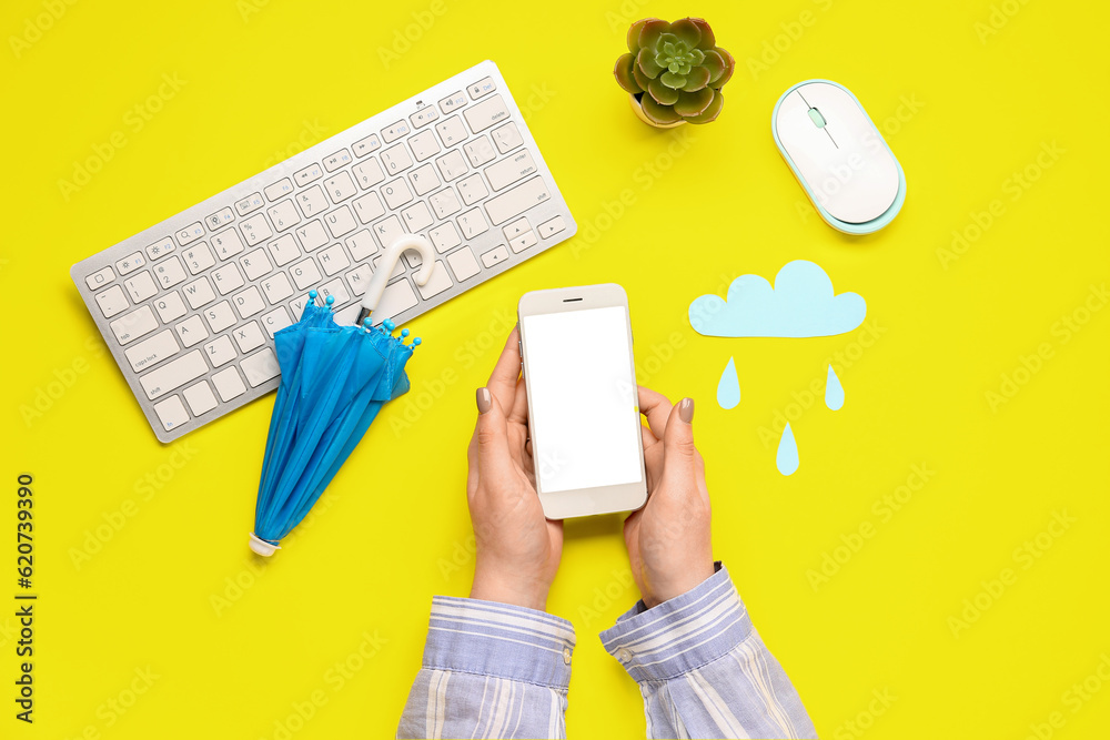 Woman with mobile phone, umbrella, paper cloud and computer keyboard on yellow background. Weather f