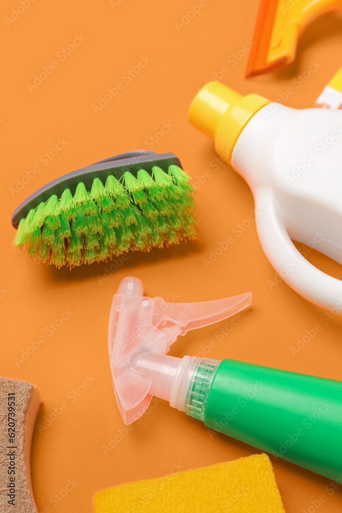 Different cleaning supplies on orange background, closeup