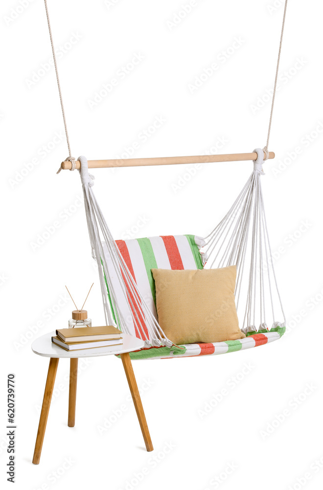 Cozy striped hammock with cushion and reed diffuser on stool against white background