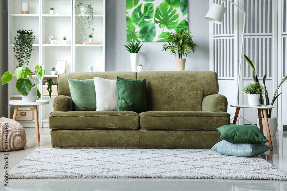 Interior of light living room with green sofa and houseplants