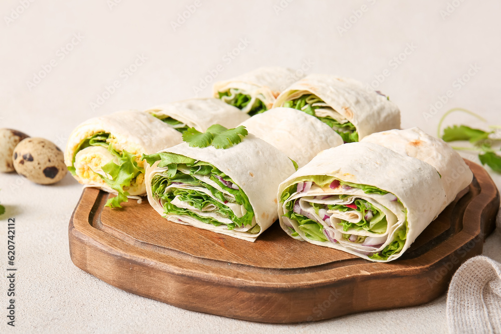 Wooden board of tasty lavash rolls with onion, egg and greens on light background