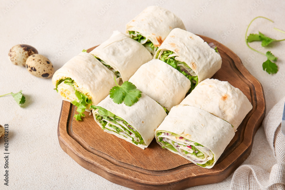 Wooden board of tasty lavash rolls with onion, egg and greens on light background