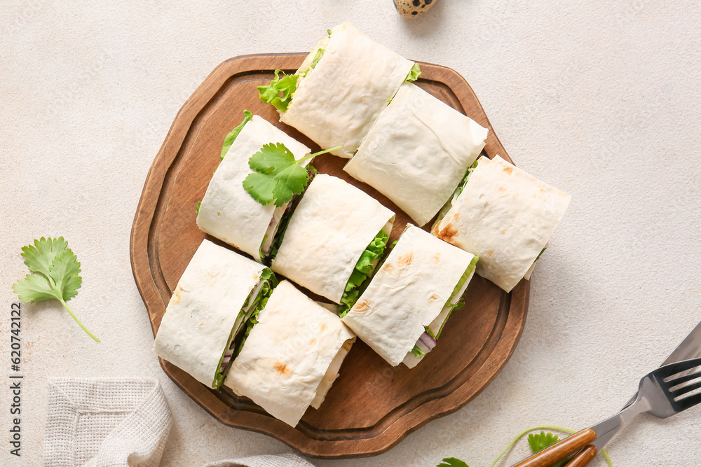 Wooden board of tasty lavash rolls with onion, egg and greens on light background