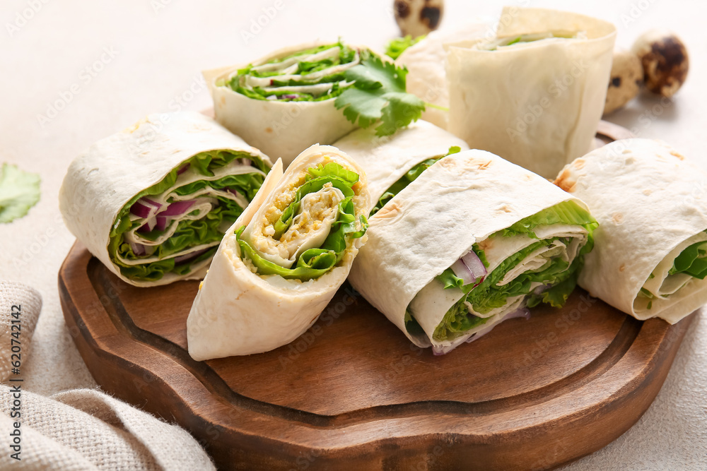 Wooden board of tasty lavash rolls with onion, egg and greens on light background