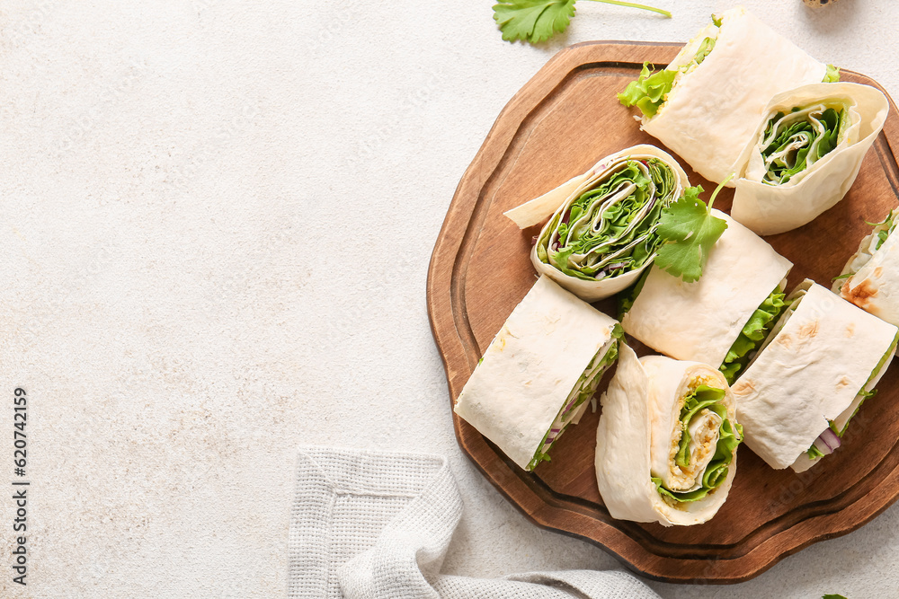 Wooden board of tasty lavash rolls with onion, egg and greens on light background