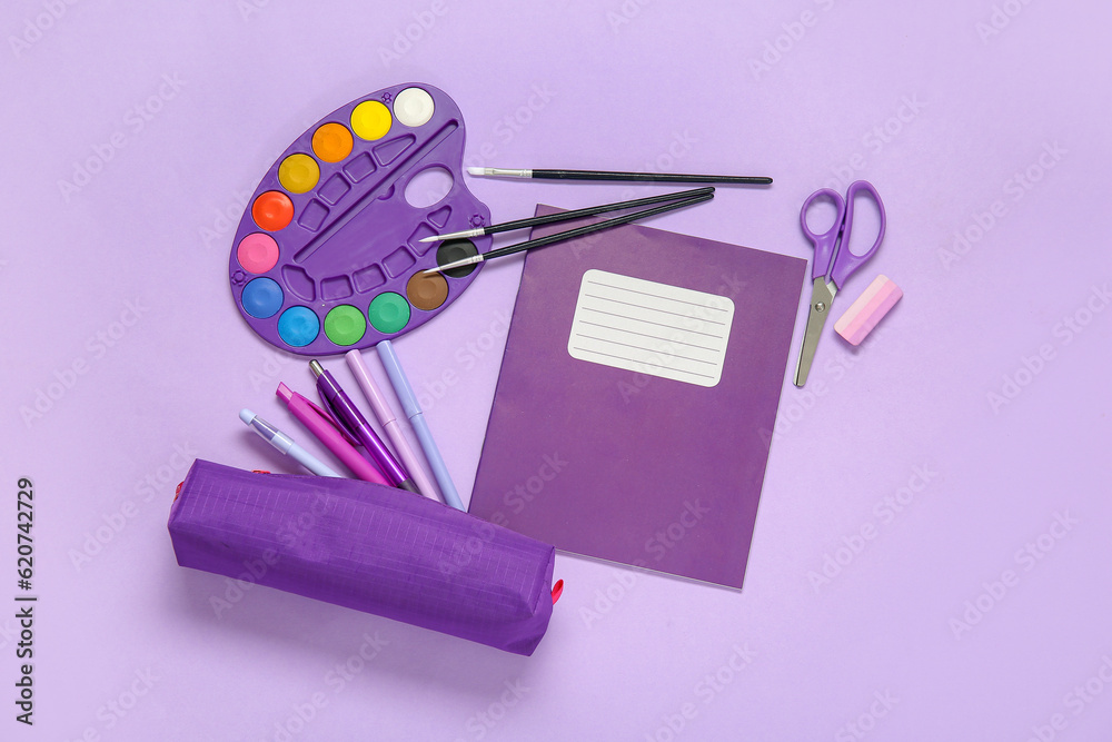 Notebook with pencil case and different stationery on purple background