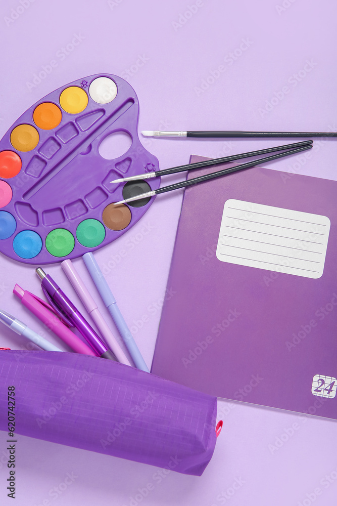 Notebook with pencil case and different stationery on purple background